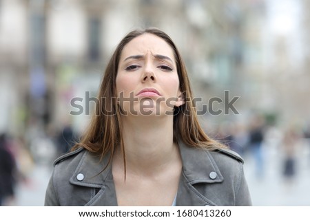 Front view portrait of a disappointed woman looking at camera on a city street Royalty-Free Stock Photo #1680413260