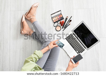 Female makeup artist with laptop and cosmetics at home