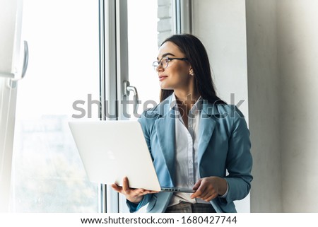 Portrait of confident young business woman. Young business woman typing an email on laptop at home office.