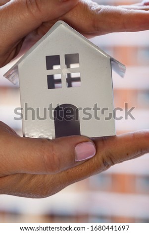 House in hands on a background of a building under construction. Buying a property.