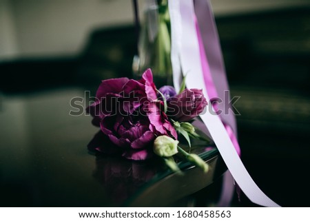 Purple peony boutonniere for groom on dark background