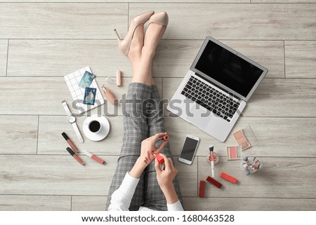 Female makeup artist with laptop and cosmetics at home