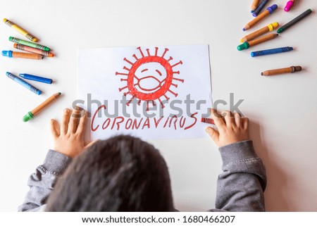unrecognizable child colors a picture about coronavirus on a white table