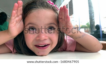 
Playful girl child covering face with hands smiling to camera