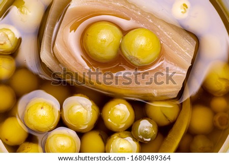 Top down macro close up view of yellow green Jurubeba peas in conservation liquid with onion