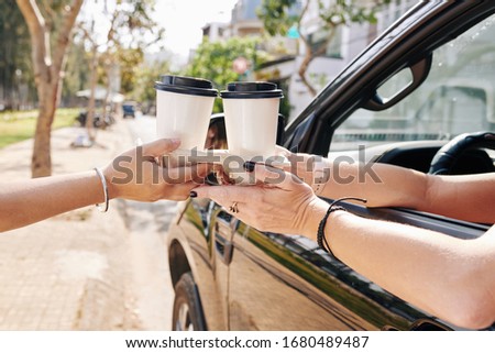 Female car driver buying two cups of take out coffee in drive through cafe Royalty-Free Stock Photo #1680489487