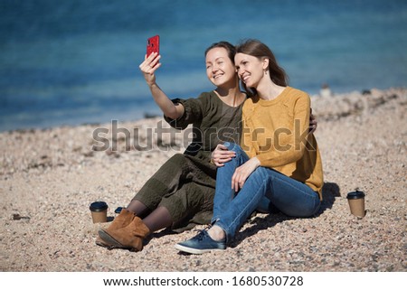 Two friends of the girl travel together and take a selfie on their smartphone. The concept of travel, tourism, coffee to take away, friendship. Place to copy.