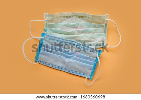 Used green surgical face masks with cosmetic stains, lipstick marks isolated on color background, cause of the spread of germs, virus or bacteria. problem of unhygienic disposal of infectious waste. Royalty-Free Stock Photo #1680560698