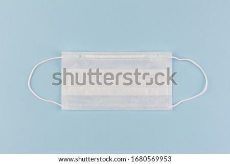 disposable medical mask on a blue background close-up , concept shortage of medical masks during the coronavirus COVIND-19 pandemic