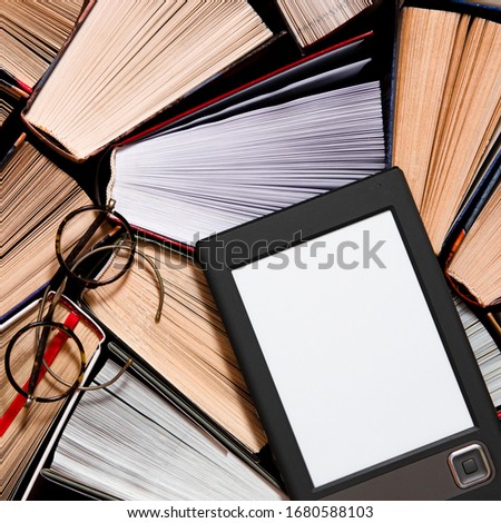 The e-book with a clean white screen rests on the open multi-colored books. ready to read Royalty-Free Stock Photo #1680588103