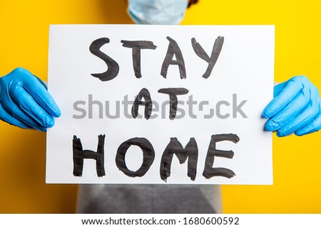 stay at home. woman in rubber gloves and a medical mask holds an inscription on a sheet of paper. Protective measures during the coronavirus pandemic