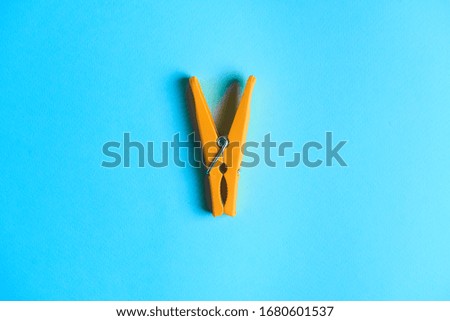 Yellow clothespin on a blue background.The object in the center of the picture.Household.