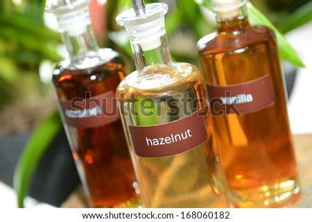 Pretty glass bottles containing hazelnut, vanilla and caramel coffee syrups for flavoring a drink.  Royalty-Free Stock Photo #168060182