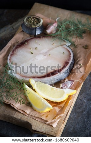 A shark steak with herbs and lemon. Dark background