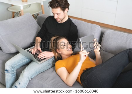 Couple using fast home internet with laptop and digital tablet. Woman and man on sofa in living room Royalty-Free Stock Photo #1680616048