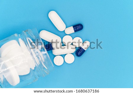 Close up of Pills spilling out of pill bottle on blue background. with copy space. Medicine concept . Top view .