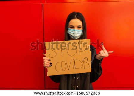 Healthy girl in mask shows  ''Stop Coronavirus'' . Concept 2019-nCov. Corona virus outbreaks.  Epidemic virus Respiratory Syndrome. Positive girl and text. text on board copy space, full body and port