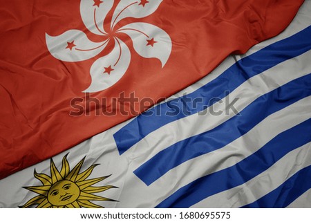 waving colorful flag of uruguay and national flag of hong kong. macro