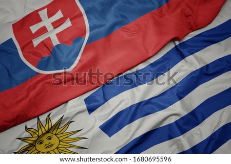 waving colorful flag of uruguay and national flag of slovakia. macro