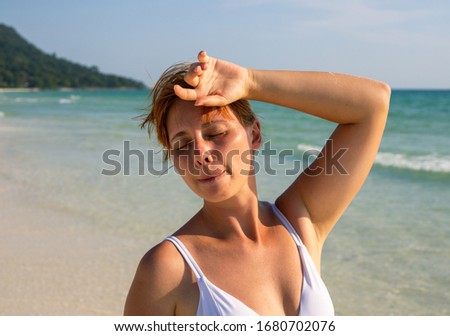 Woman in bikini suffering from sunstroke on tropical beach. Medicine on summer vacation photo. Woman with sun stroke holding head. Tropical holiday threat. Outdoor healthy tip. Tourist sunstroke