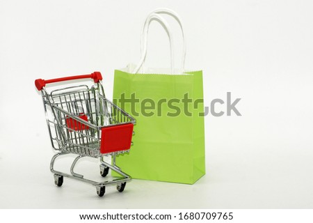 Shopping trolley with paper bag exposed on white background                 