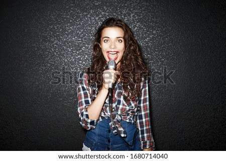 Karaoke party. Time to sing! Crazy casual curly chic girl singing with microphone. Studio shot