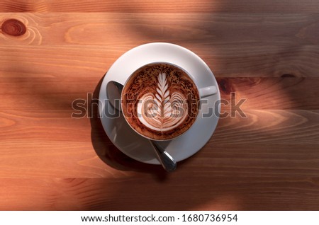 latte or Cappuccino with frothy foam, coffee cup top view on table in cafe.
