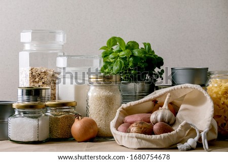Food supplies crisis food stock for quarantine isolation period. Different glass jars with grains, pasta, cans of canned food, toilet paper, chalkboard handwritten chalk lettering Stay home and relax. Royalty-Free Stock Photo #1680754678