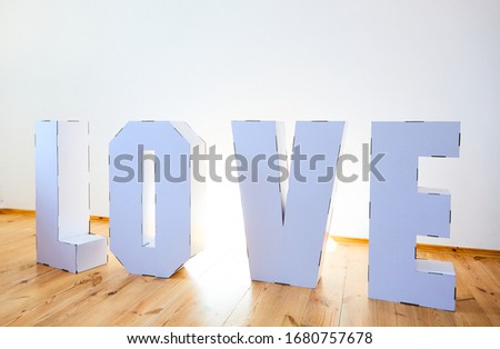 3D Standing Letters forming word LOVE from white cardboard on a light background. Relationship concept.