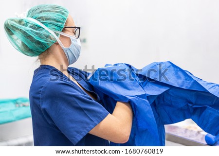 Covid-19. Female nurse puts on protective cloths. Personal protective equipment in the fight against Coronavirus disease . Royalty-Free Stock Photo #1680760819