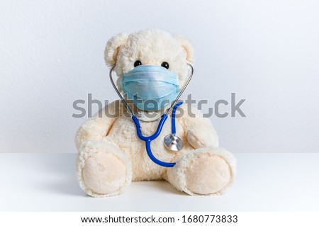 Cute teddy bear doctor with protective medical mask and stethoscope. Concept of pediatric treatment of illness, hygiene, epidemic and virus protection for child patient. Fluffy toy on white background Royalty-Free Stock Photo #1680773833