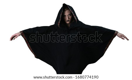 A girl in a black robe makes magic movements with her arms spread wide. On white background. Witchcraft.