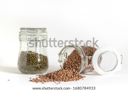Mash and red lentils are stored in glass jars with a yoke. One container lies next to spilled raw materials. Food stocks for future use. Safe and environmentally friendly food storage.