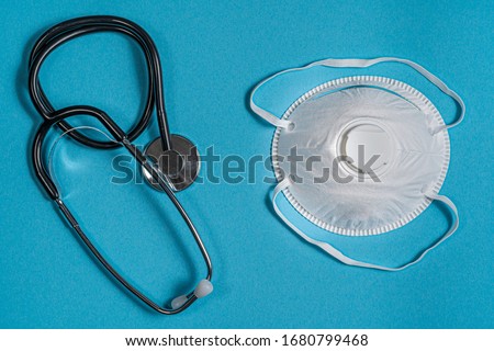 Stethoscope and Face Mask N95 Respirator on Blue Surface Background, Top-down Perspective.