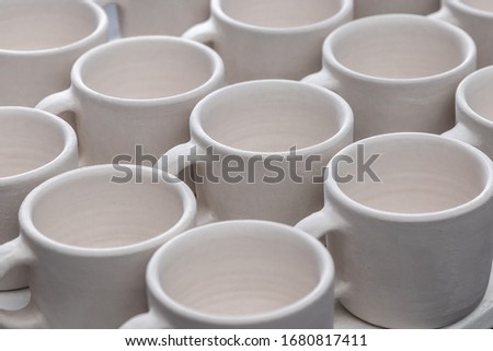 Many ceramic white cup pattern in the potters studio. Seamless abstract creative cover background, close-up. Minimal concept of creativity and art