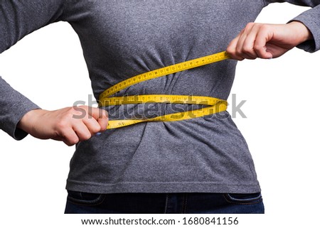 A woman in a gray T-shirt pulls herself together with a yellow centimeter. The concept of losing weight.