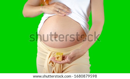 Young pregnant woman belly uncovered on isolated background with a violin sign. A concept photo of a positive influence of listening to classical music during pregnancy on the fetal brain development.
