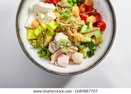 Couscous with chiken and avocado top view. Poke bowl of fresh vegetables and tofu cheese. Delicious meal with cut cucumber and tomato. Traditional dish decorated with sauce and pepper.