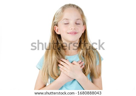 Little sincere adorable girl closed eyes holding hands on chest feeling gratitude pose isolated on white background, arms on heart gesture of love appreciation gratitude, adoption concept