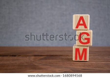 AGM (Annual general meeting) acronym on wooden cubes on dark wooden backround. Business concept. Royalty-Free Stock Photo #1680894568