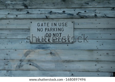 Sign on wooden garage door requesting people not to park in front and block access.