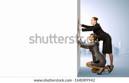 Two businesswoman pushing blank white banner. Place for text