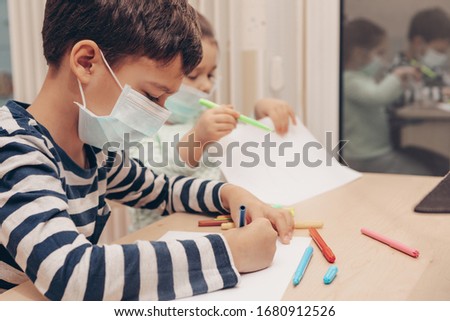 Cute children boy and girl in medical mask is sitting at home in quarantine. Сhildren play constructor after disinfection hands. Entertainment for the children during quarantine. Self isolation.      