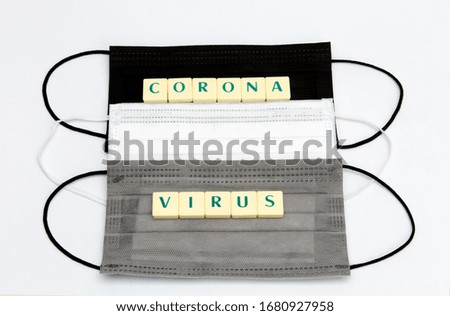 Medical protective face masks in different colors and Corona Virus text. Coronavirus and Covid-19 concepts. Epidemic, infection, quarantine, cold, flu. Horizontal close-up on white background.