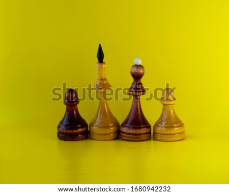 Chess. Four wooden chess pieces on a yellow background. Concept.