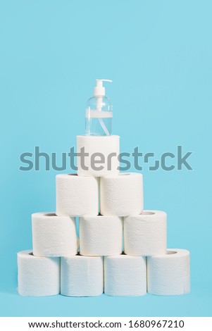 Stock of soft white toilet paper and liquid antiseptic in a transparent bottle on blue background. In case of a virus outbreak