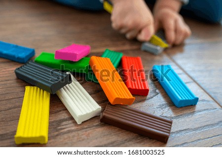 A child plays with colored plasticine for modeling on the wooden floor