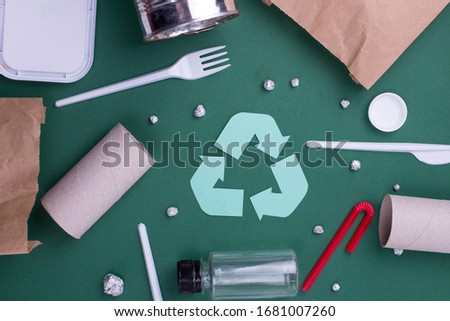 Reuse reduce recycle flat lay concept with plastic, paper, and polyethylene waste. Template image with recycling symbol.