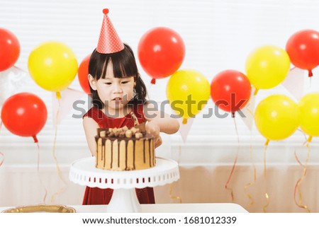 toddler girl cut birthday cake celebrating her birthday at home