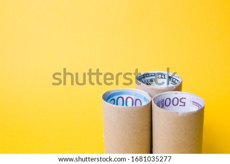 banknotes of different countries inside the sleeve from the toilet paper yellow background copy space, economic crisis due to the coronavirus pandemic, quarantine 2020
